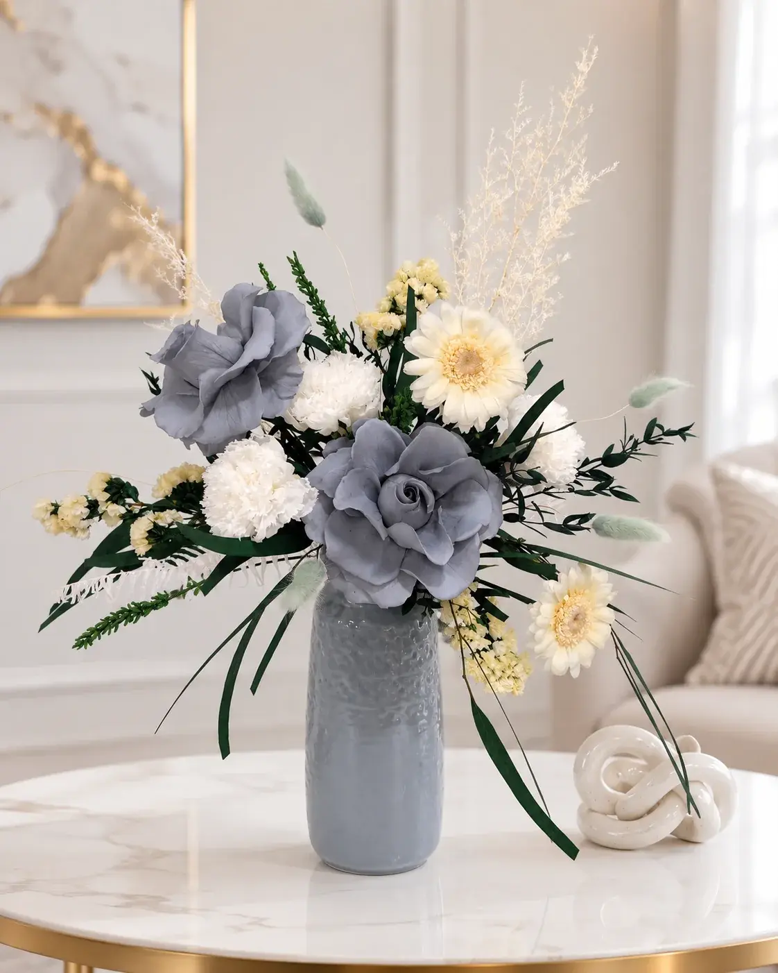 Blue Serenity arrangement with blue-grey roses, white blooms and greenery in a blue-grey vase on a marble coffee table.