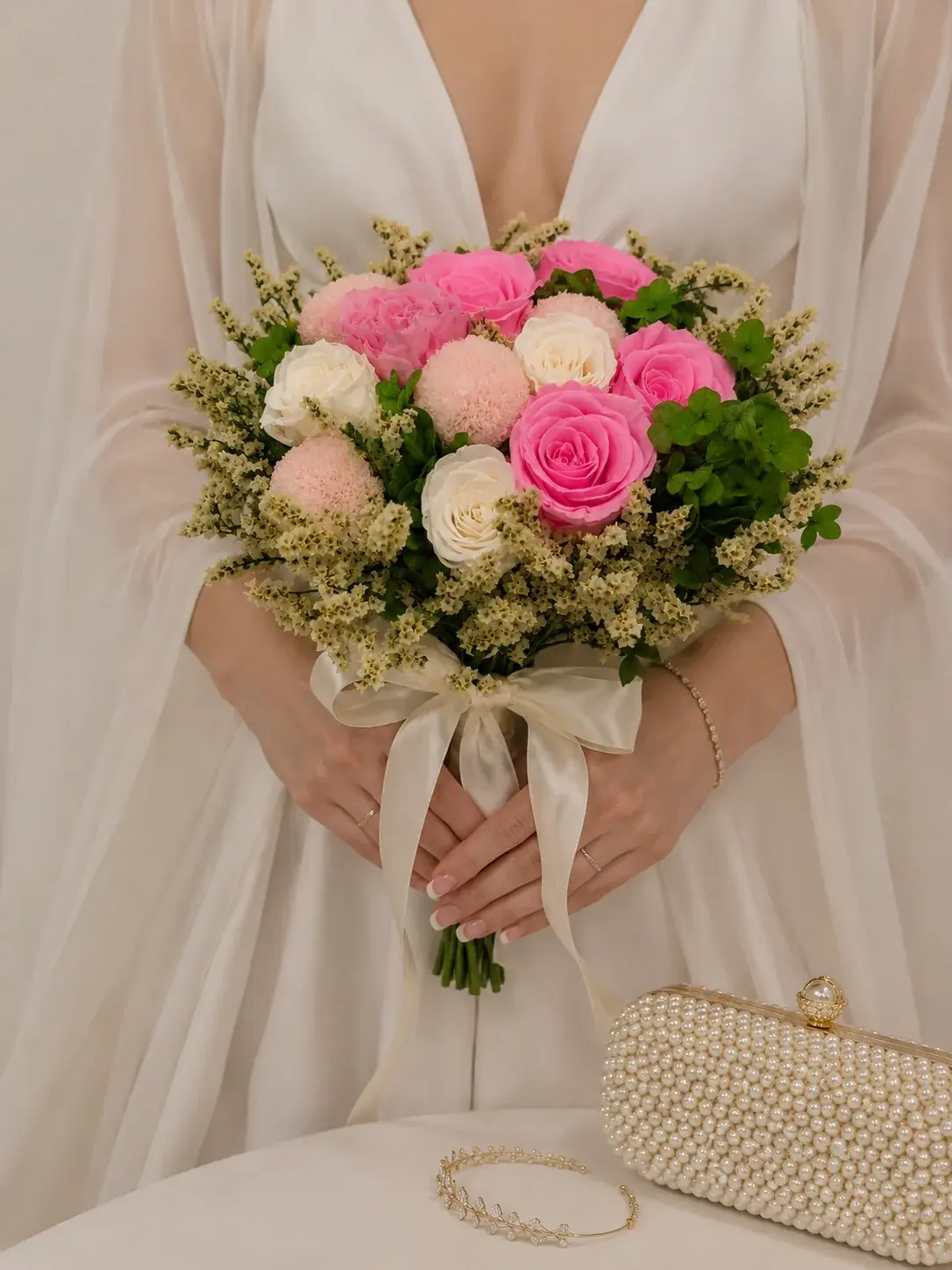 Bride holding the Cherish wedding bouquet with pink and ivory roses, blush blooms, greenery and an ivory satin bow.