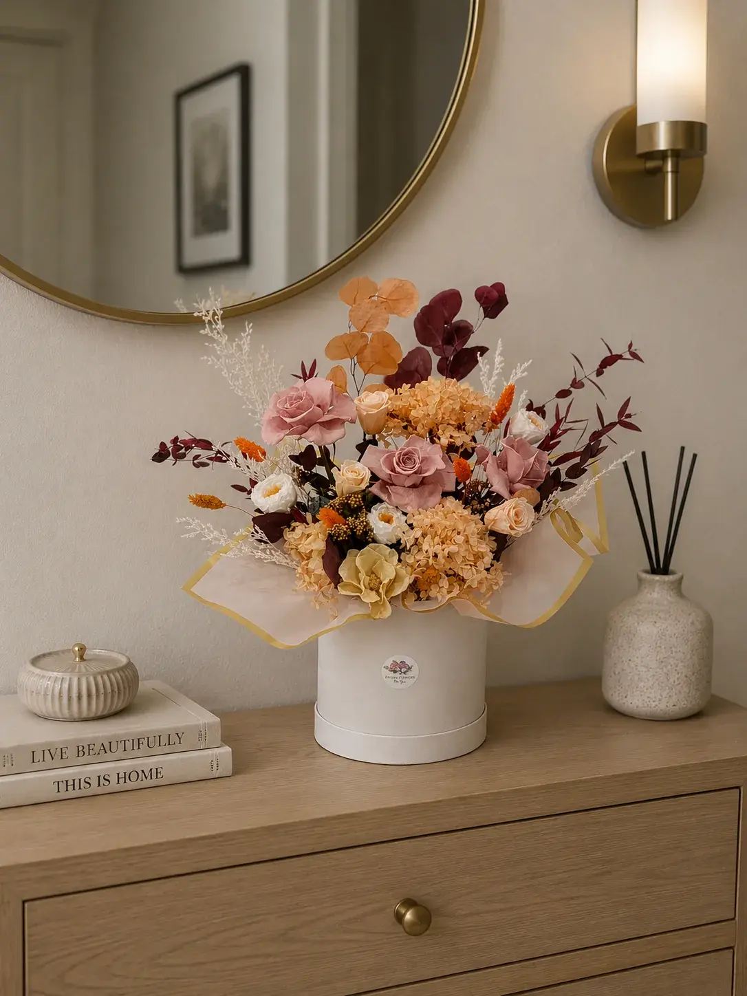 Warm Elegance flower box with dusty pink roses, peach hydrangea and burgundy foliage on a console by a mirror.