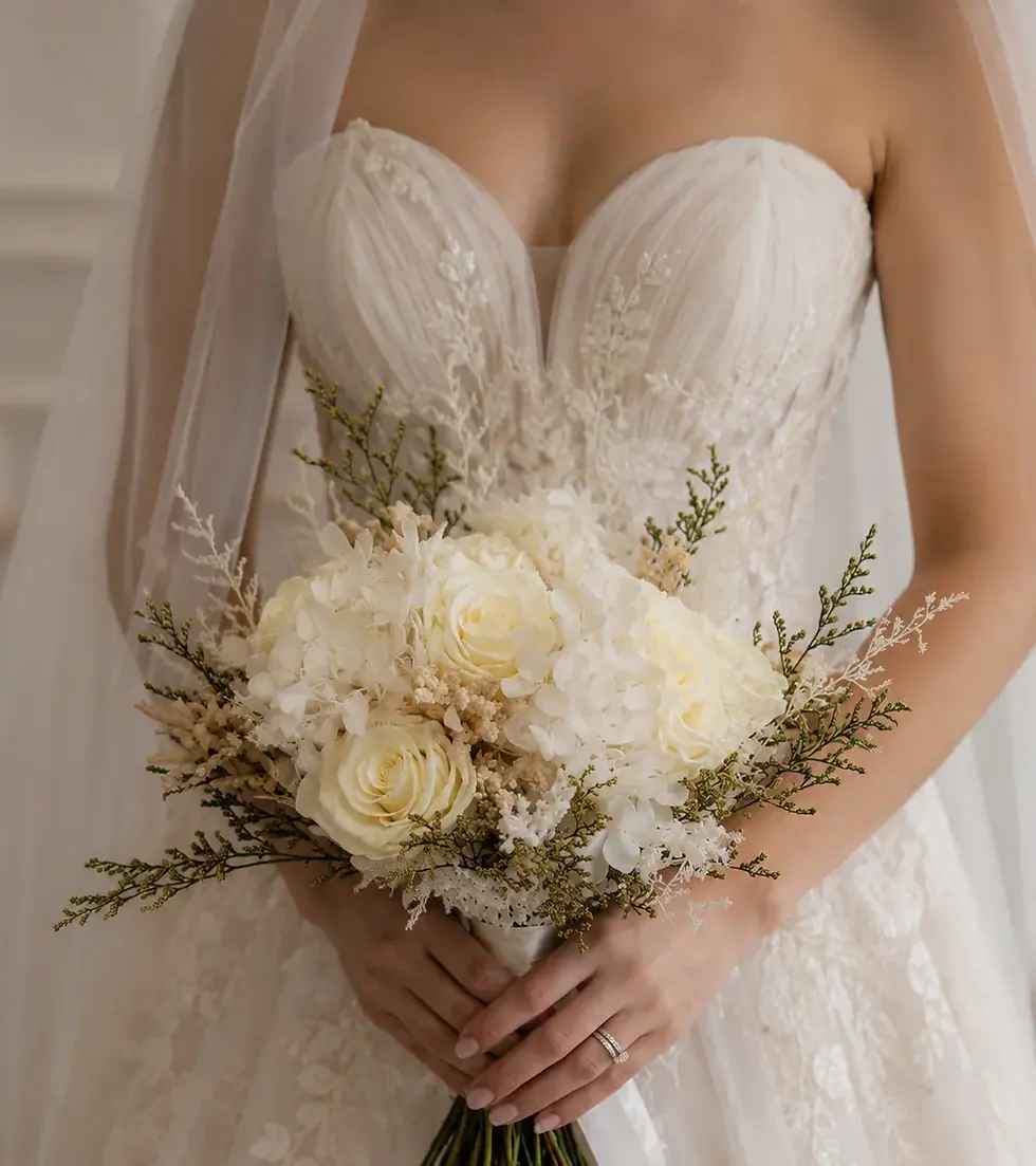 Bride holding the Pearl wedding bouquet of ivory roses, white hydrangea blooms and delicate greenery against her lace gown.