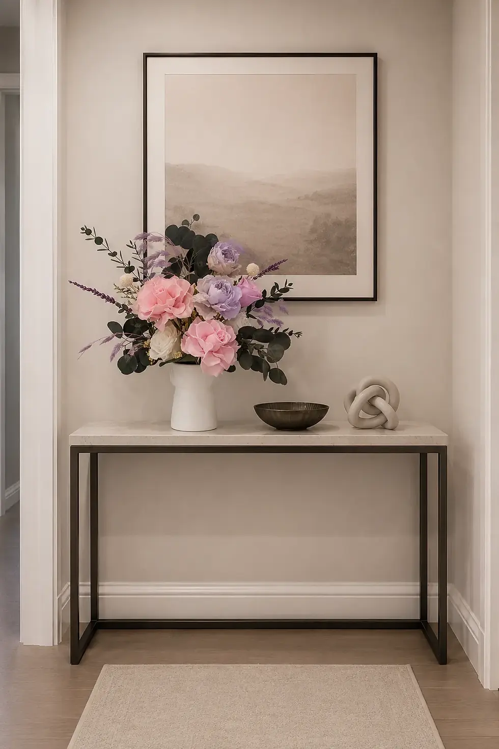 Harmony arrangement with pink roses, lavender and white blooms and dark eucalyptus in a white vase on a bedside table.