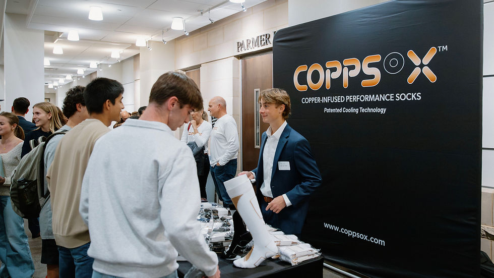 Crowd gathered around Coppsox display table as founder Grant Shreiner explains the brand’s cooling performance socks at the Impact Venture Challenge.