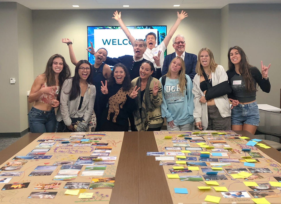 11 people posing behind 2 tables displaying cards.