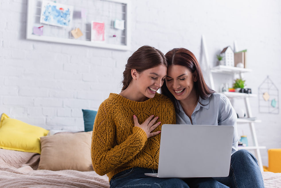 A mother and daughter sitting on the bed looking at a lap top screen together smiling. This represents the need for social anxiety treatment katy, tx and emdr for depression katy, tx 77493. This also represents the need for anxiety treatment katy, tx and a therapist for teen depression.