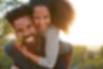 An African American couple outside with the man giving the woman a piggyback ride, both smiling. This represents the need for marriage counseling katy, tx 77494. This also represents the need for a marriage therapist katy, tx and a marriage counselor katy, tx 77494.