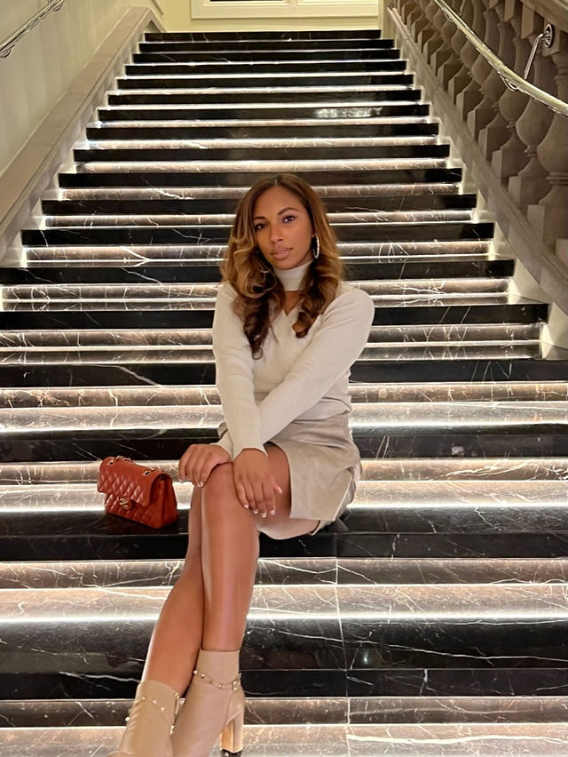 Angelina Darrisaw styled in neutrals sitting on stairs at Leading Women Defined