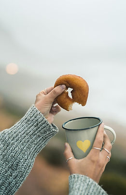 Hands holding a donut and coffee free from guilt or shame