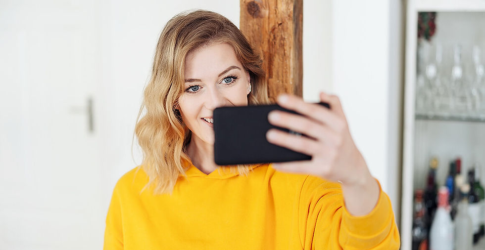 Young woman in a yellow sweater taking a selfie, representing the initial step of applying or introducing oneself as an egg d