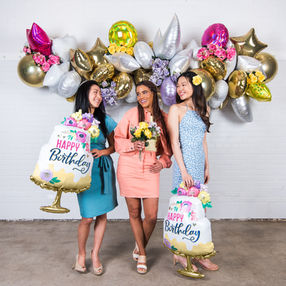 group of young women celebrating a birthday with wine glass shaped balloons