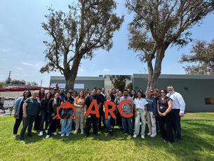 Group of ARC staff and volunteers posing outdoors, holding large orange letters spelling _ARC_