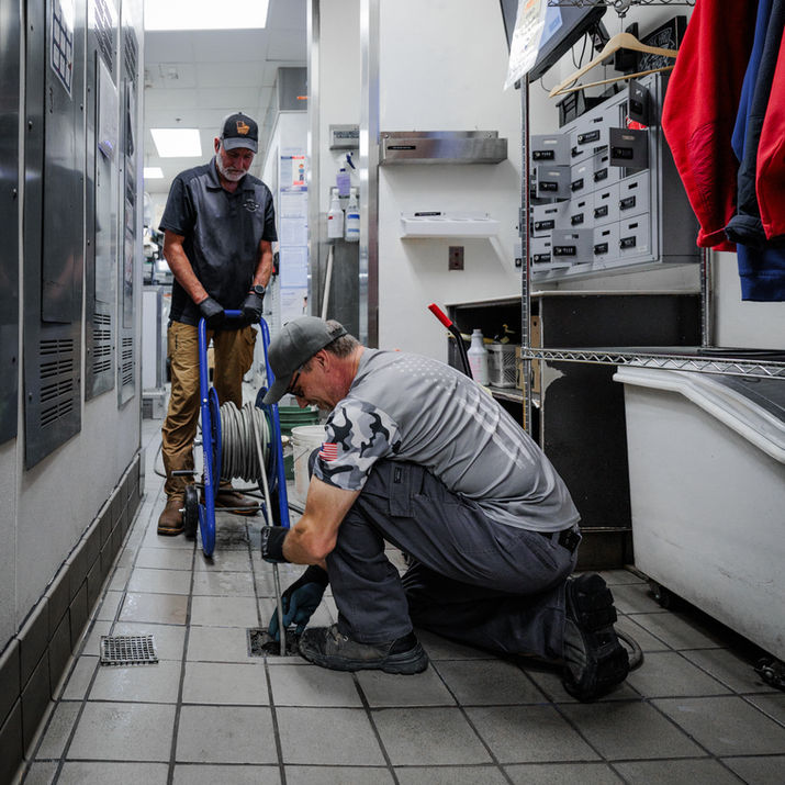 Plumber cleaning commercial drain