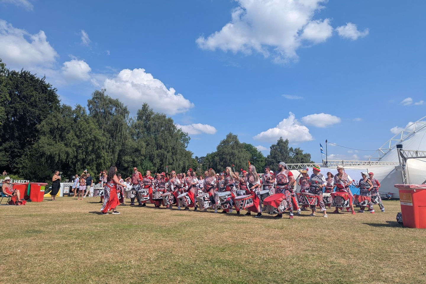 Batala drummers playing in a field with blue sky overhead