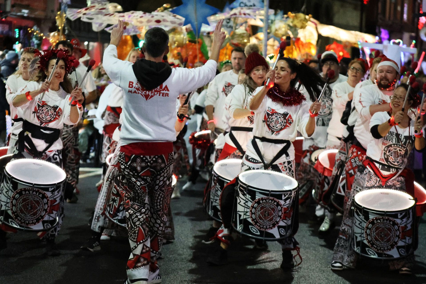 Batala Manchester players in parade formation with a caller in the foreground facing them