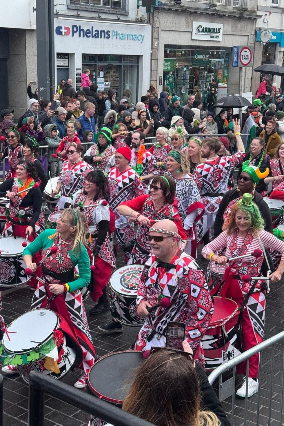 Group of people playing drums in a lively street performance.