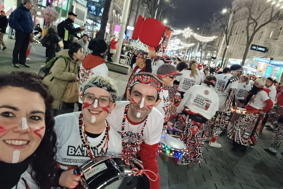 Batala Manchester players in festive attire holding drums on a street.