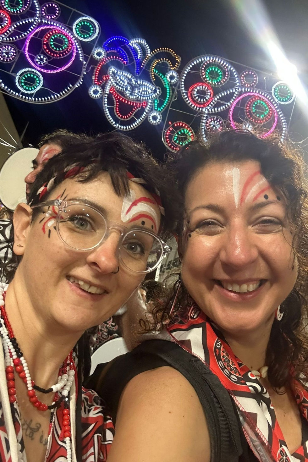 Two people smiling with festive face paint.