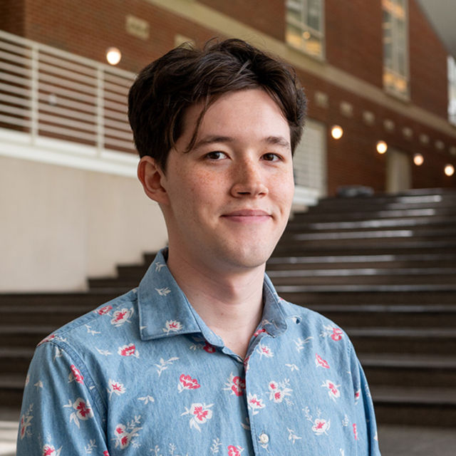 headshot of young man Summer Intern wearing a blue button-down collared shirt with pink and white floral pattern