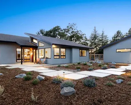 Contemporary single-story custom home at dusk with a paver courtyard in Auburn Lake Trails, CA