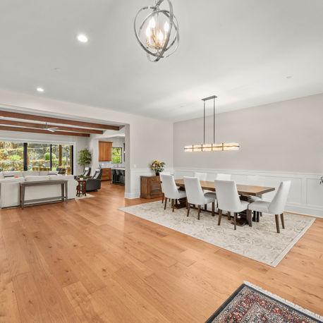 Formal dining room with a linear chandelier and white oak floors at The Ridge