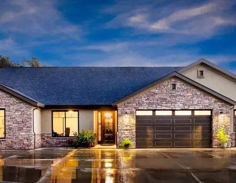 Front elevation of The Sierra semi-custom home with stone accents and a lit entry