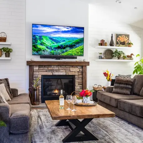 Living room with a stone fireplace and shiplap walls in The Sierra semi-custom home