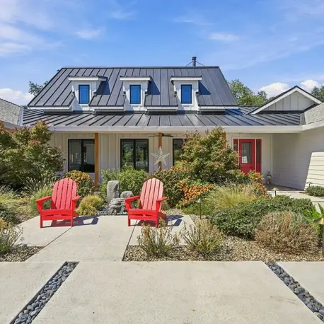 Front courtyard garden with red chairs under a blue sky