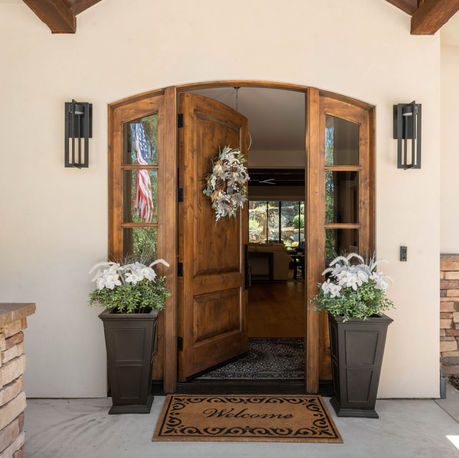 Arched knotty alder entry doors flanked by planters at The Ridge
