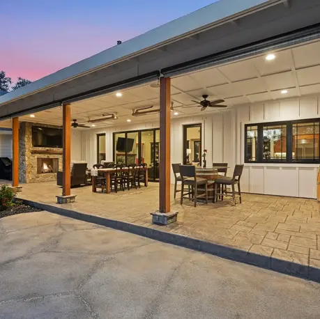 Covered back porch at dusk with wood posts, stamped concrete, and dining areas