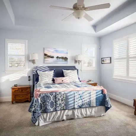 Primary bedroom with a tray ceiling and plantation shutters in an Auburn semi-custom home