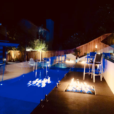 Pool, fire feature and swim-up bar lit in blue at night in a Rocklin, CA backyard