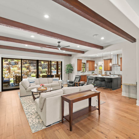 Great room with exposed beams and a fireplace opening to the kitchen at The Ridge