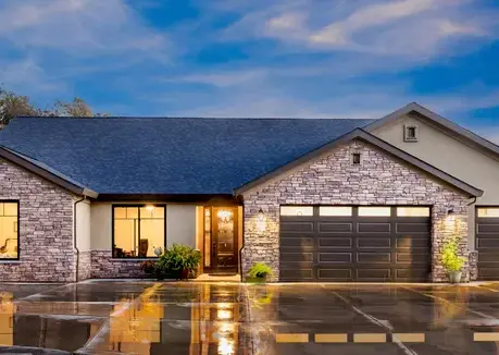 The Sierra semi-custom home at dusk with a stone facade and two-car garage