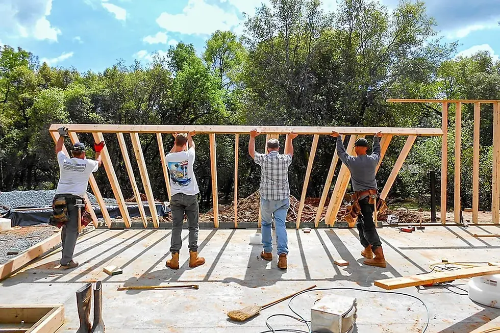 Sherman Homes crew raising a framed wall on the slab of a custom home under construction in the Sierra foothills