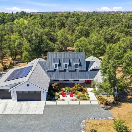 Drone view of the front with rooftop solar and gravel motor court