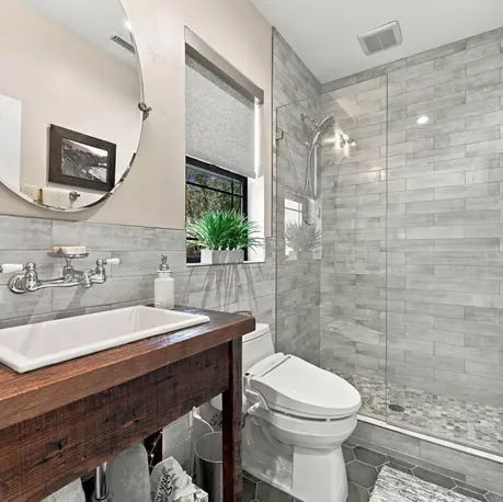 Guest bath with reclaimed-wood vanity, trough sink, and round mirror