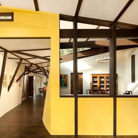 Yellow-walled gallery hallway with timber bracing and interior glazing at Canopy House