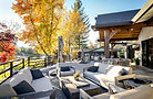 Lakeside deck with lounge seating and an outdoor kitchen framed by fall foliage