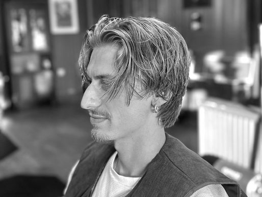 Men's longer textured haircut with a middle part at Barbery Coast in North Beach, San Francisco
