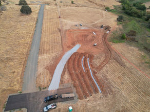 Excavator grading a building pad on a rural foothill property in Placer County, CA