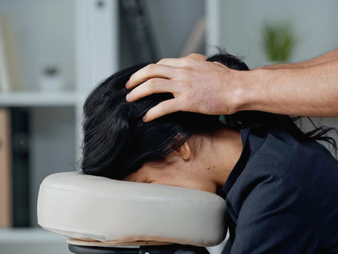 On-site chair massage session supporting workplace wellness, with therapist working on neck and shoulders.
