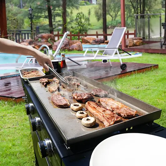 Steaks cooking on an outdoor flat top griddle near a backyard pool in Carson City, NV.