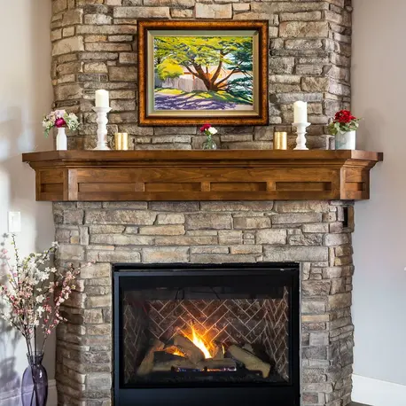 Stacked-stone fireplace with a carved wood mantel in an Auburn semi-custom home