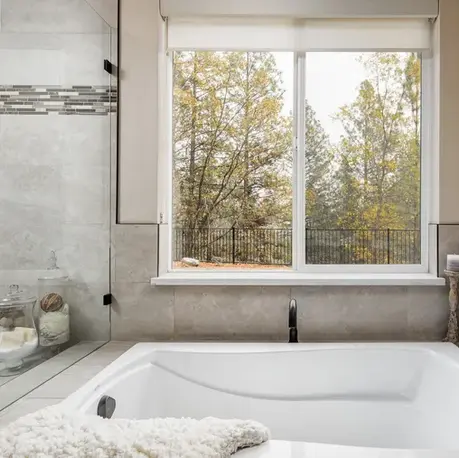 Soaking tub set beneath a window overlooking the pines in The Alpine, Winchester Country Club
