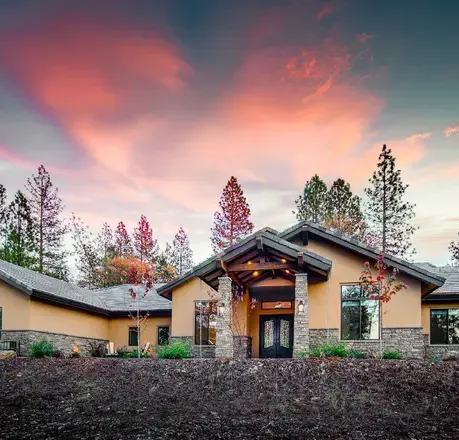 Front elevation of The Motherlode at dusk with a blue front door and stone wainscot