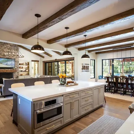 Great room and kitchen with reclaimed ceiling beams and a stone fireplace in Christian Valley, CA