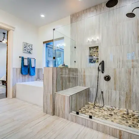 Walk-in shower with a pebble floor and bench in The Motherlode primary bath