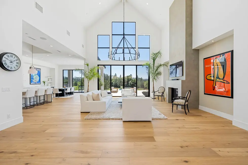 Foothill custom home living room with floor-to-ceiling black-framed windows, polished concrete floors and pine-covered hillside views