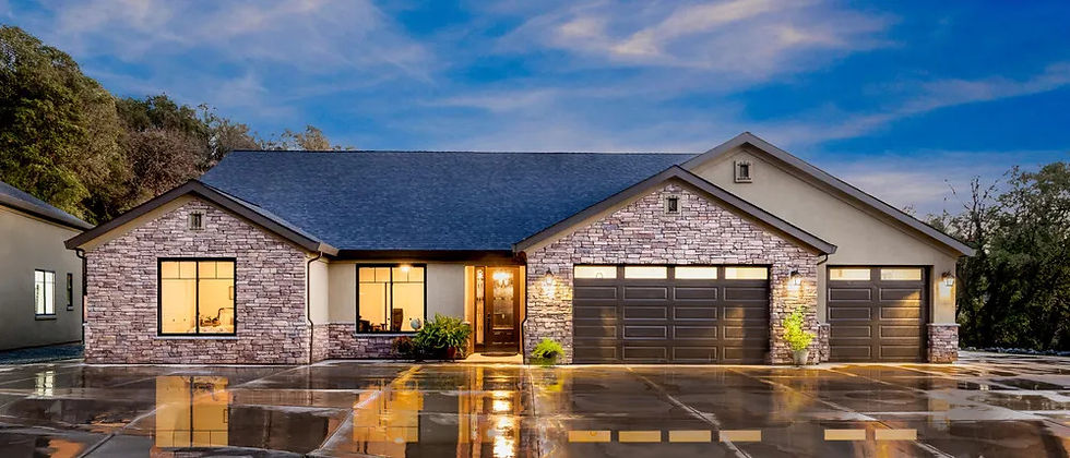 The Sierra semi-custom home at dusk with a stone facade and two-car garage