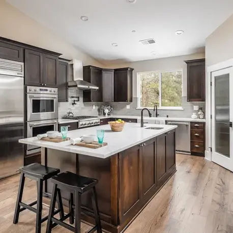 Kitchen with dark alder cabinetry, a quartz island and built-in appliances in The Alpine