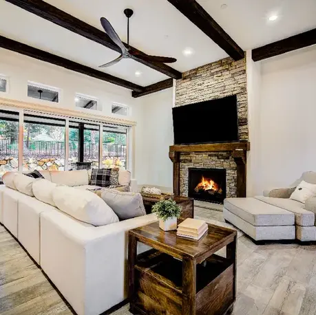 Living room with a stacked-stone fireplace and timber mantel in The Motherlode